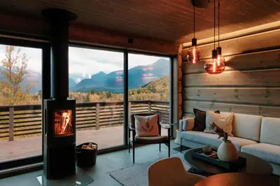 a living room with a fireplace and a view of the mountains at Dream Cabin Mivo X - Mountain Views and Idyllic Location at Strandafjellet in Stranda