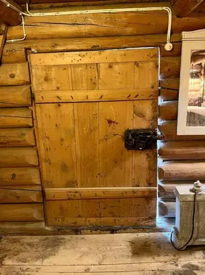 a wooden wall with a door in a room at Traditional barn -Stabbur - wifi og sauna in Baukål