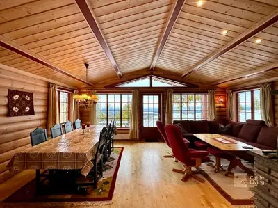 a dining room with a large wooden table and chairs at Large cabin with Sjusjøens best view, sauna and ski in out in Ringsaker