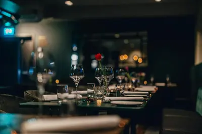 a table with glasses and plates and a red rose on it at Biologen Herdla in Askøy
