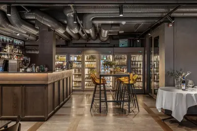 a restaurant with a bar with yellow stools at Biologen Herdla in Askøy