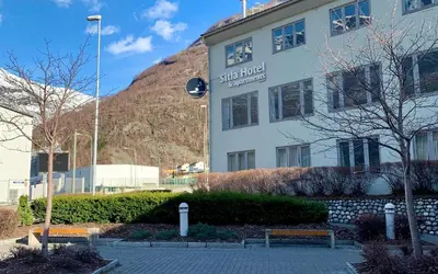 a building in front of a mountain with two benches at Sitla Hotel & Apartments in Øvre Årdal