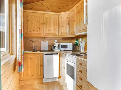 a kitchen with wooden cabinets and a white stove top oven at 6 person holiday home in Ånneland-By Traum in Ånneland