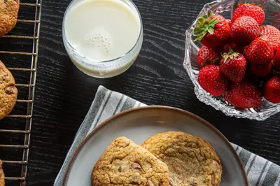 a table with cookies and strawberries and a glass of milk at 7 Min to Fjord - Alpine Stay in Stranda in Stranda