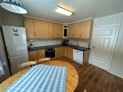 a kitchen with a table and a white refrigerator at Enesi holiday house in Hestenesøyra