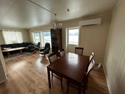 a living room with a wooden table and chairs at Enesi holiday house in Hestenesøyra
