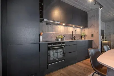a kitchen with black cabinets and a table at Ground Floor Exclusive Apartment with Sauna - Near Geiranger and the Norwegian Fjords in Stranda