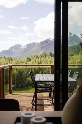 a table and chairs on a deck with a view of mountains at Nordic Luxury Apartment - Private Sauna & Panoramic Mountain Views in Stranda