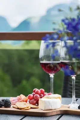 a glass of wine and a plate of cheese and crackers at Nordic Luxury Apartment - Private Sauna & Panoramic Mountain Views in Stranda