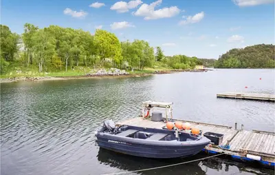 a blue boat docked at a dock on a lake at Beautiful Home In Sveio With Wifi in Sveio