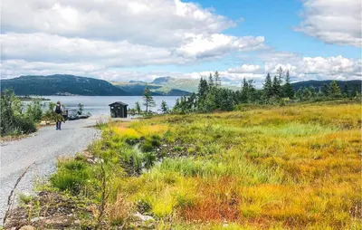 a person walking down a dirt road next to a lake at Nice Home In Tuddal With Kitchen in Tuddal