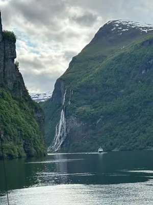 a boat in a lake in front of a waterfall at Beach front appartments in design eco-villa in Ulsteinvik