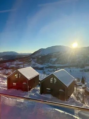 two houses in the snow with the sun in the background at Rindabotten Panorama in Sogndal