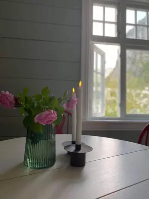 a table with two candles and a vase of flowers at Valldal Sentrum Overnatting in Valldal