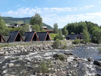 a group of buildings next to a river at Hallingparken in Gol