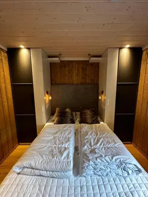 a large white bed in a bedroom with wooden walls at Nice apartment on Geilotunet, Close to city center in Geilo