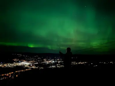 a person standing on top of a hill watching the northern lights at Nice apartment on Geilotunet, Close to city center in Geilo