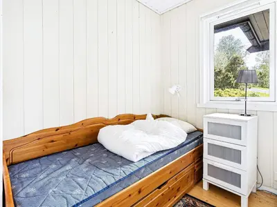 a bedroom with a wooden bed and a window at 6 person holiday home in Ånneland-By Traum in Ånneland