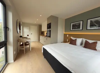 a bedroom with a large white bed and a table at Odda City Apartments in Odda