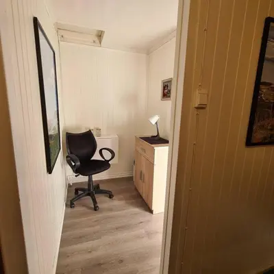 a room with a chair and a desk with a lamp at Koselig hus med hage i Herøy på Sunnmøre. in Røyra