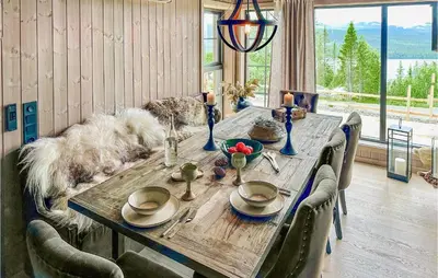 a wooden table with chairs and a dog sitting around it at Gorgeous Home In Gålå With Sauna in Gålå
