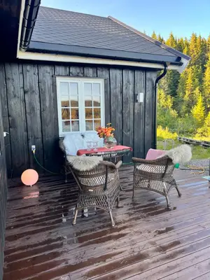 a patio with two chairs and a table on a deck at På solsiden av Gaustatoppen in Tuddal