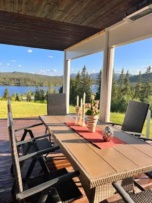 a wooden table on a deck with a view of a lake at På solsiden av Gaustatoppen in Tuddal