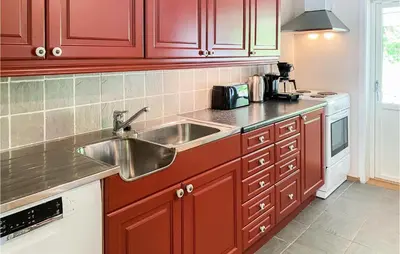 a kitchen with red cabinets and a stainless steel sink at 4 Bedroom Beach Front Home In Skodje in Skodje