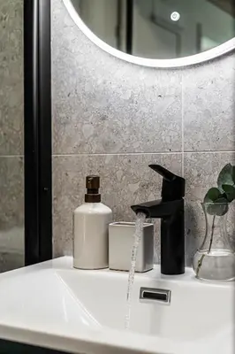 a bathroom sink with a soap dispenser and a mirror at Charming and bright apartment in Ålesund city in Ålesund