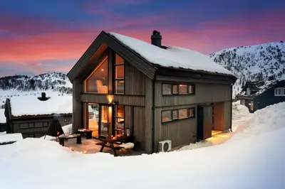 a small house in the snow with a sunset at Ski-in-out from the door Alpine XC Mountain views in Torvetjørn