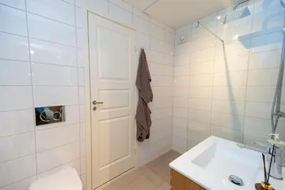 a white bathroom with a sink and a door at Vakker leilighet - stor parkeringsplass 10min fra Bergen in Bergen