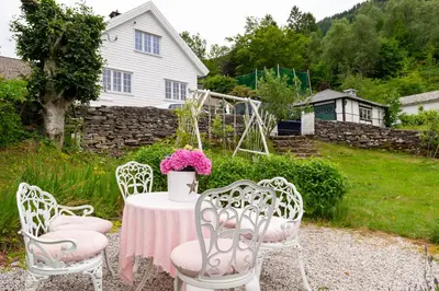 a table with chairs and a table with pink flowers at Vakker leilighet - stor parkeringsplass 10min fra Bergen in Bergen
