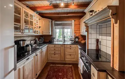a kitchen with wooden cabinets and a large window at Nice Home In Svingvoll in Svingvoll