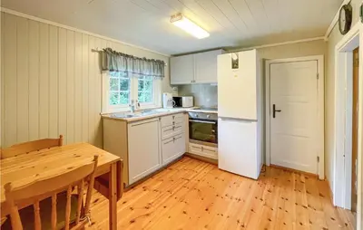a kitchen with a table and a white refrigerator at Nice Home In Sagstua With Lake View in Linstad