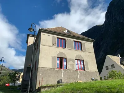 a building with red windows in front of a mountain at Fjordshelter dorm in Tysso
