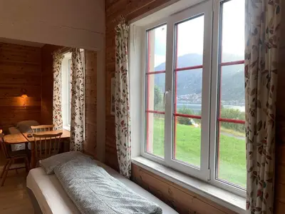 a bedroom with a bed and a window with a table at Fjordshelter dorm in Tysso