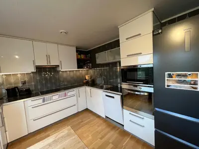 a kitchen with white cabinets and black appliances at Røstad Apartment - with Kitchen and Free Parking in Trondheim