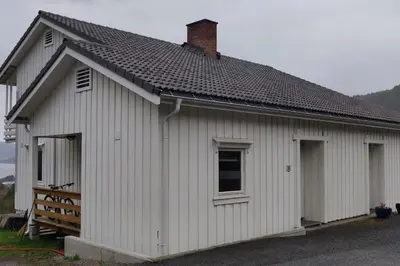 a white building with a gambrel roof at Hus med utsikt på leira . 4 sengeplasser. in Leira