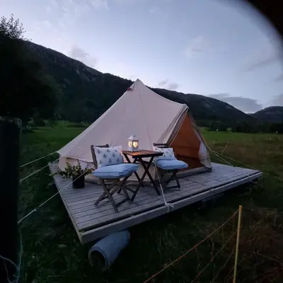 a tent with a table and chairs on a deck at Flatheim Glamping in Viksdalen