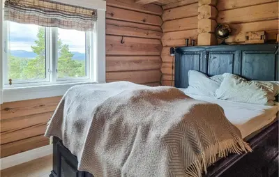 a bedroom with a bed with a blanket and two windows at 5 Bedroom Gorgeous Home In Tynset in Tynset