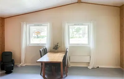 a dining room with a table and two windows at 2 Bedroom Stunning Home In Dovre in Dovre
