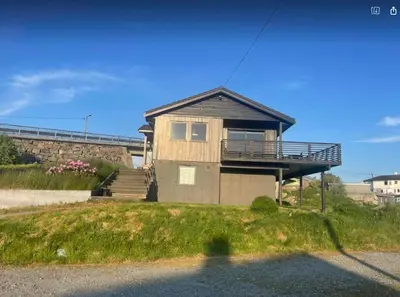 a house with a balcony and stairs on a hill at Nautnes Seaside Villa in Nautnes