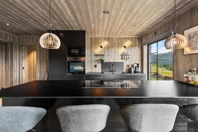 a kitchen with a black counter top and chairs at Hodlekvevegen 307 in Sogndal