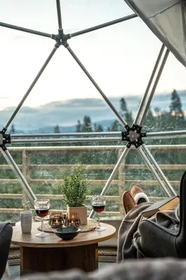 a table with two glasses of wine in front of a window at Arctic Dome Gudbrandsdalen in Sør-Fron