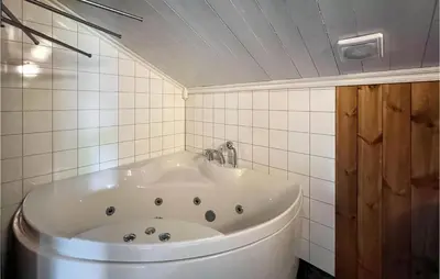 a bath tub in a bathroom with white tiles at 4 Bedroom Beautiful Home In Nord-Torpa in Nord Torpa