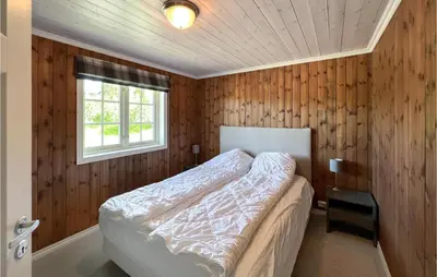 a bedroom with wooden walls and a bed with a window at 4 Bedroom Beautiful Home In Nord-Torpa in Nord Torpa