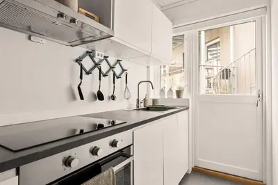 a white kitchen with a sink and a window at Dinbnb Apartments I Views & Street Parking in Sandviken in Bergen
