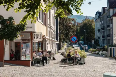 a group of people sitting in chairs on a street at Dinbnb Apartments I Characteristic Townhouse with Bathtub in Bergen