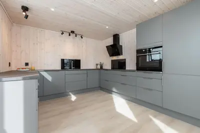 a large kitchen with white cabinets and a wooden floor at Hodlekvevegen 308 - Flott hytte midt i skisenteret in Sogndal
