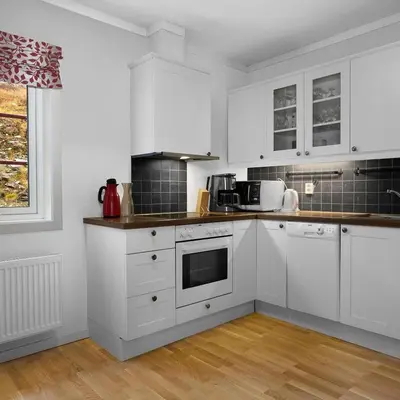 a white kitchen with white cabinets and a window at Smuksjøseter Fjellstue in Høvringen